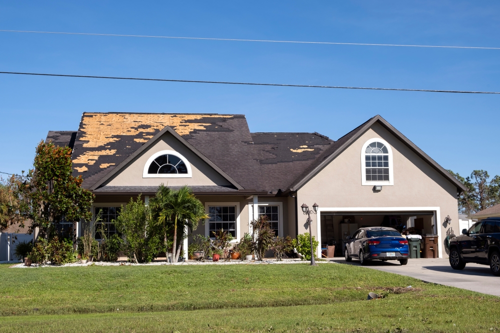 Damaged house roof with missing shingles after hurricane in Shawnee Mission, KS.