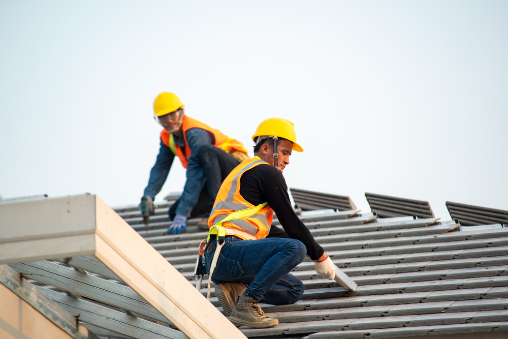 roofing contractors using a nail gun to install new commercial roof in Overland Park, KS