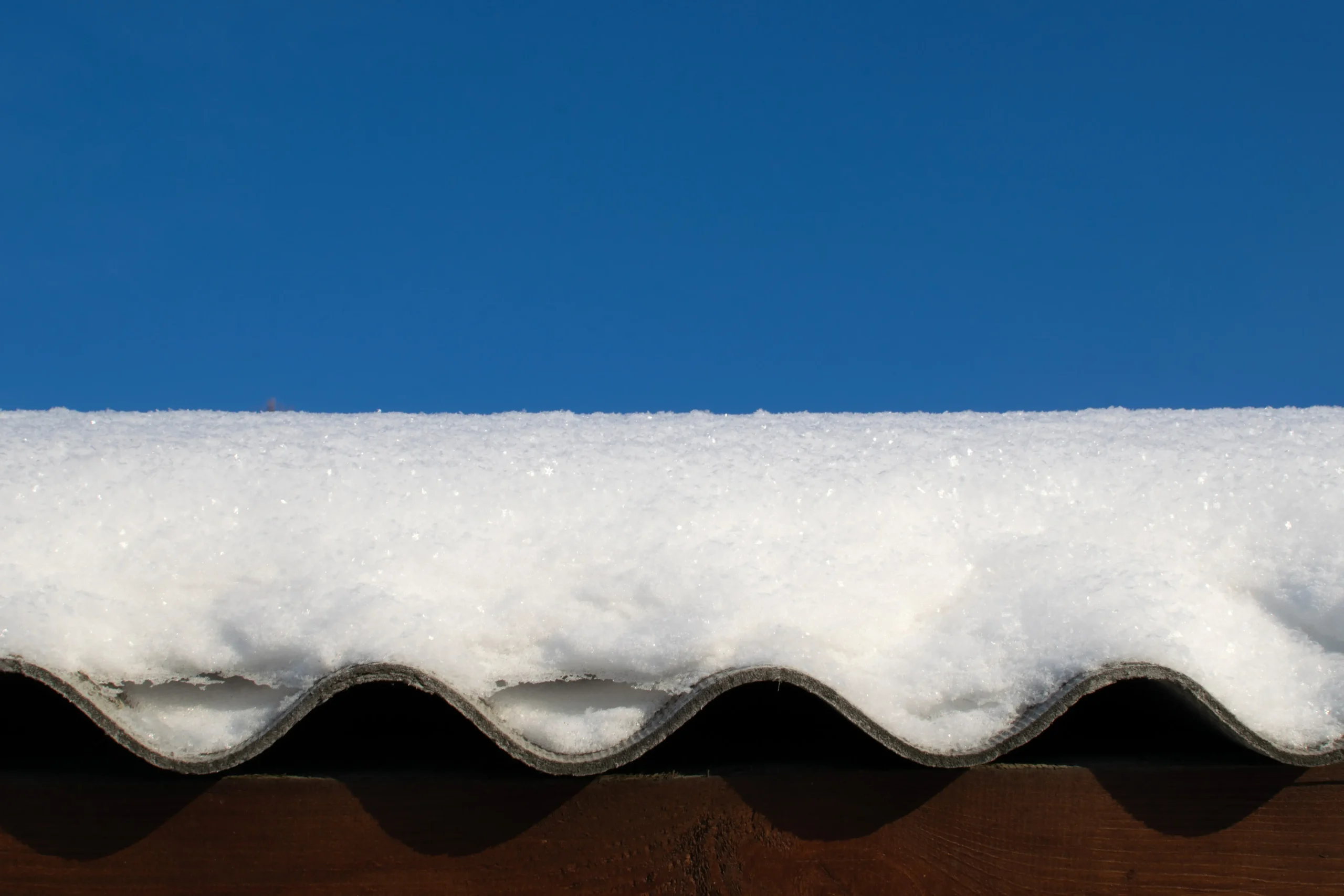 Winter in Ohio Layer of snow lay on the roof of a wooden house, shining with a bright clear blue sky.